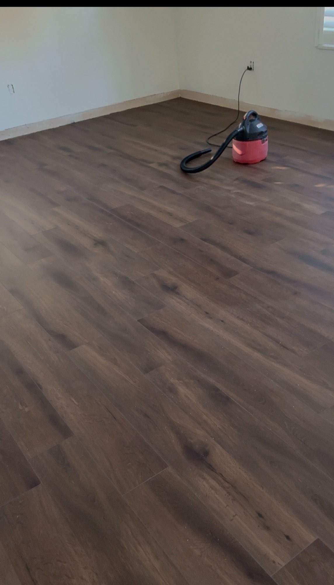 Dark LVP flooring freshly installed in empty room